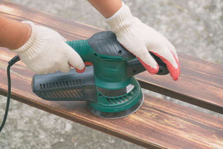 Sanding a wood with orbital sander outdoorの写真素材