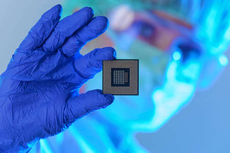 An engineer working in a laboratory wearing a special uniform and protective gloves holds new...