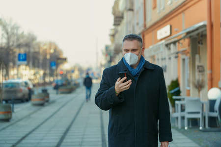 Man wearing protection mask walking on a city street.の写真素材