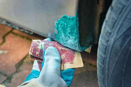 Repairing a rust hole in a car body with puttyの写真素材