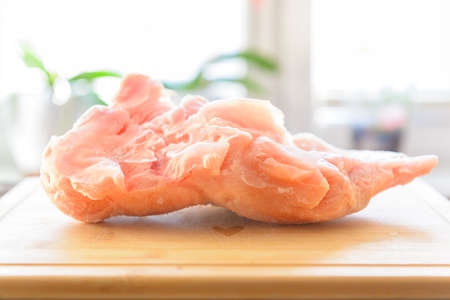 Frozen turkey breast fillet on a wooden board in the kitchen
