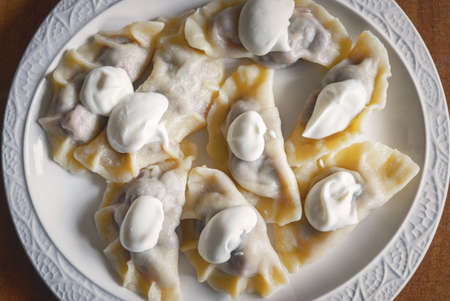 Fresh dumplings with cherry filling and cream on a plateの写真素材