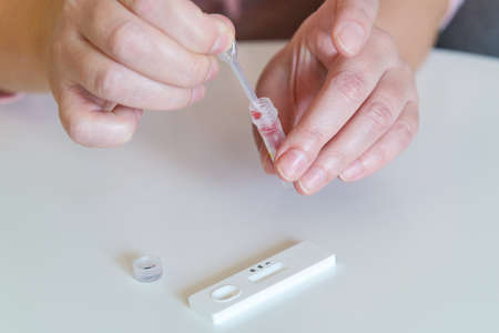 The woman takes a blood sample with a pipette from his finger to perform a  testの写真素材