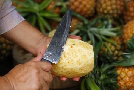 A person in the process of Peeling a pineappleの写真素材