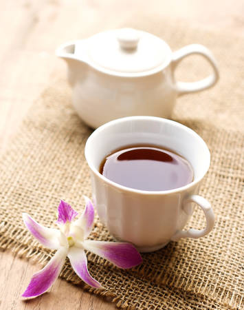 cup of black coffee  with purple orchid and burlap cloth on wooden tableの写真素材