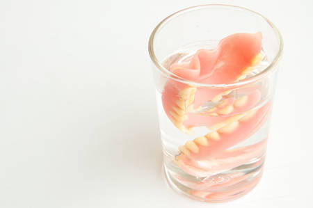 An artificial denture in a glass of water on isolated backgroundの写真素材