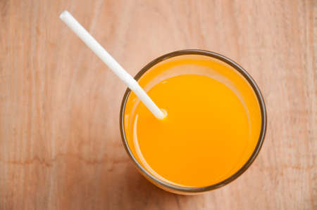 Glass of freshly pressed orange juice with sliced orange half on wooden tableの写真素材