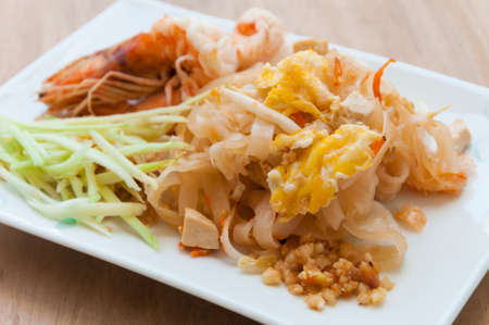 Seafood pad Thai dish of stir fried rice noodles on a square white plateの写真素材