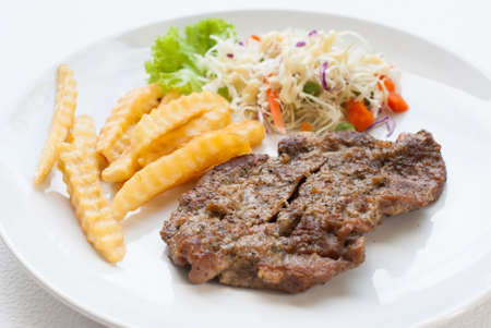 steak served with crisp golden French fries and fresh green herb saladの写真素材