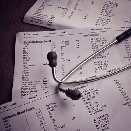 A stethoscope on the top of a blood test result, dark toneの写真素材