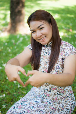 Beautiful girl show love sign outdoorの写真素材