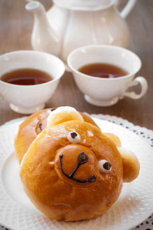 Sweet bun and cup of tea on wooden table