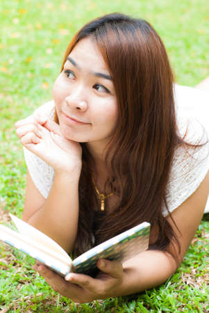 beautiful asian woman reading a book in the gardenの写真素材