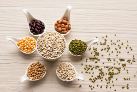 Different kinds of bean seeds, lentil, peas in dish on wooden table, macrobiotic food or healthy foodの写真素材
