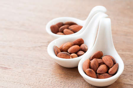 Salted almonds in white spoon on wooden boardの写真素材
