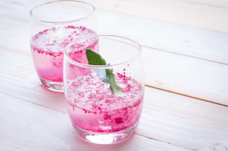 Pink Cocktail with fresh rose petals on wooden tableの写真素材