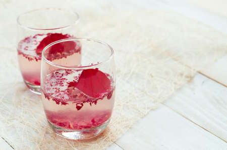 Pink Cocktail with fresh rose petals on wooden tableの写真素材
