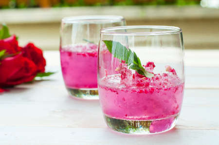 Pink Cocktail with fresh rose petals on wooden tableの写真素材