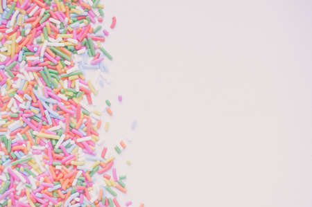 Sugar sprinkle dots, decoration for cake and bekery, a lot of sprinkles in a bucket on white wooden board backgroundの写真素材