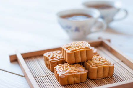 Retro vintage style Chinese mid autumn festival foods. Traditional mooncakes on table setting with teacup.の写真素材