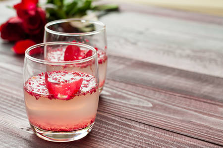 Pink Cocktail with fresh rose petals on wooden tableの写真素材