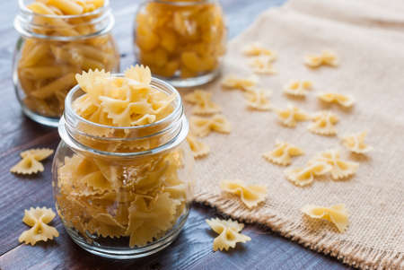 Bow tie pasta in mason jar on wooden boardの写真素材