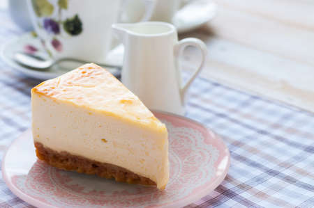 Slice of new york style cheesecake with a cup of teaの写真素材