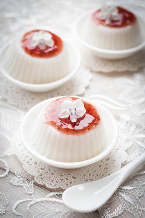 Panna cotta with raspberry sauce on white lace background, italian dessertの写真素材