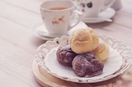 cream puff (Choux Cream) with a cup of tea on white wooden board, vintage toneの写真素材