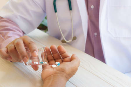doctor giving pills to a middle aged patientの写真素材