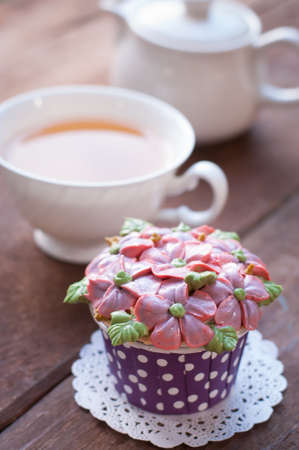 home made sponge cupcakes with flowers buttercream frosting on wooden background. Afternoon tea conceptの写真素材
