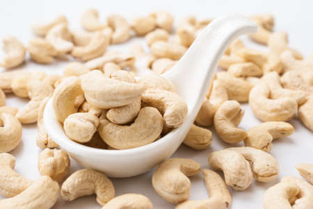 raw cashew nuts with white ceramic spoon on wood tableの写真素材