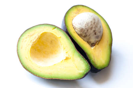 Ripe avocado cut in half on white wooden background