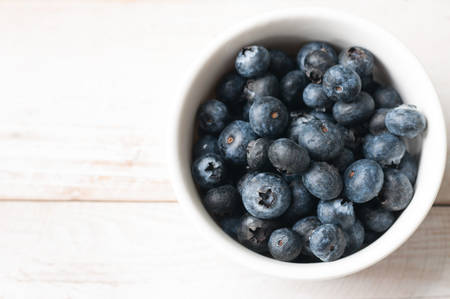 Blueberries on white ramekin placed on white wooden boardの写真素材