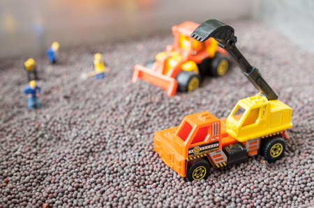 miniature people with bull dozer and Excavator toy with black mustardの写真素材