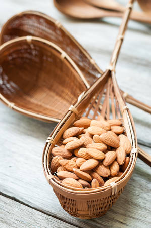 almond, in bamboo ware on wooden backgroundの写真素材