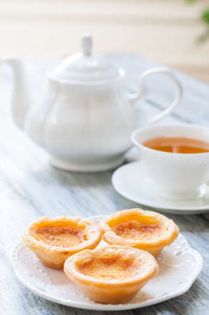 portuguese egg tart on wooden board with tea