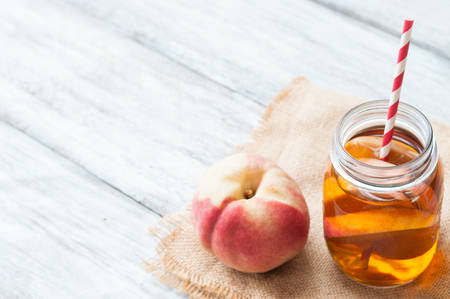 Peach tea on burlap and wooden backgroundの写真素材
