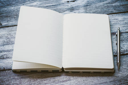 Open book with pencil on wooden board