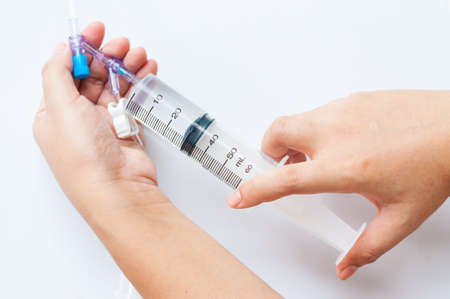 Nurse hand with medical syringe connected to container with medicationの写真素材