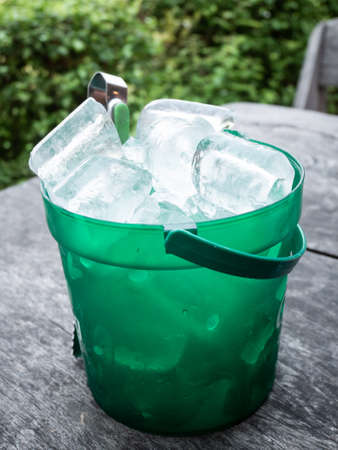 Ice in a plastic bucket on wooden tableの写真素材