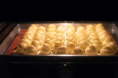 Baking choux pastry in ovenの写真素材