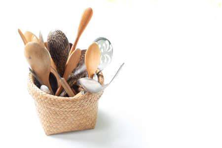 Wooden spoon in bamboo basket, isolated on white backgroundの写真素材