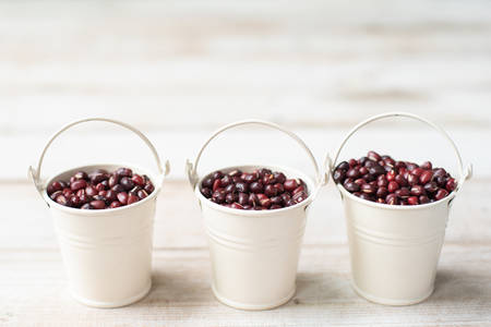 Kidney beans in white aluminium buckets on wooden background