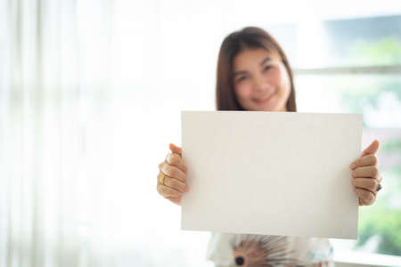 Beautiful woman holding white blank paperの写真素材
