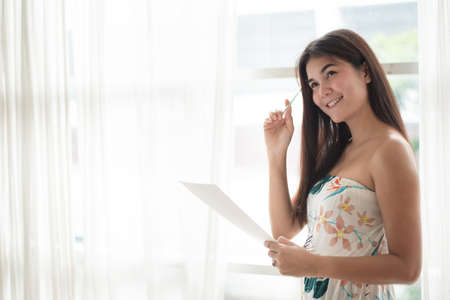 Woman holding paper and pen while thinking a new projectの写真素材