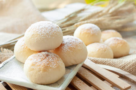 Bun with icing topping on wooden backgroundの写真素材