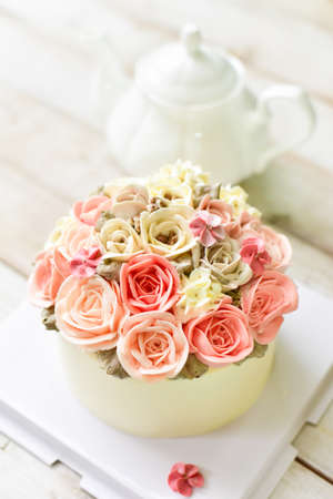 Pink Buttercream flower cake with teapot on wooden backgroundの写真素材