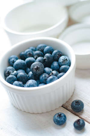 Blueberries on white ramekin placed on white wooden boardの写真素材