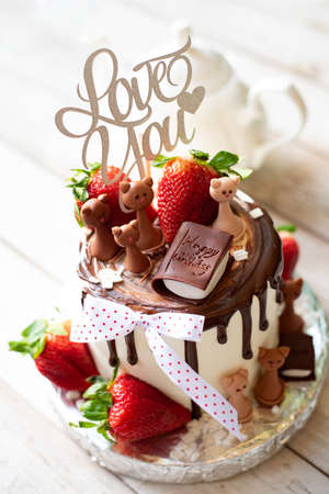 Chocolate cake with strawberries on a white wooden background. Happy birthday.